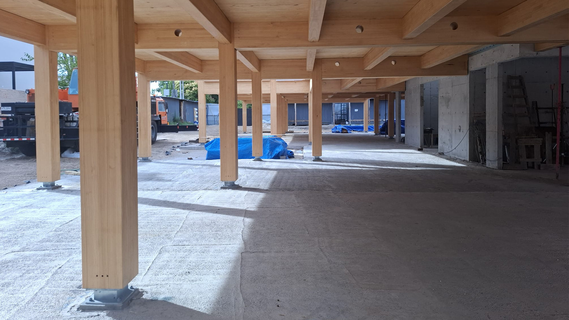 Mass timber structure with CLT beams and columns in construction, highlighting timber protection on site and structural system performance.